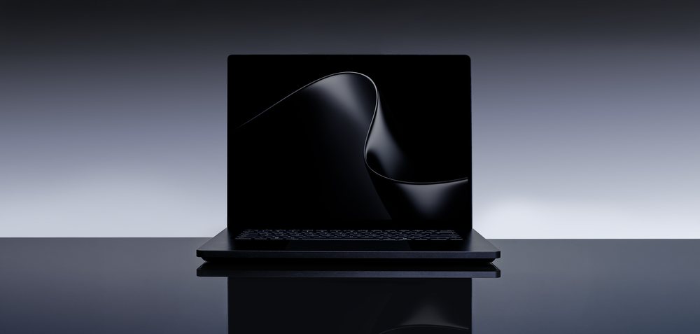 Surface Laptop Ultra in Nightfall, open on a reflective dark surface