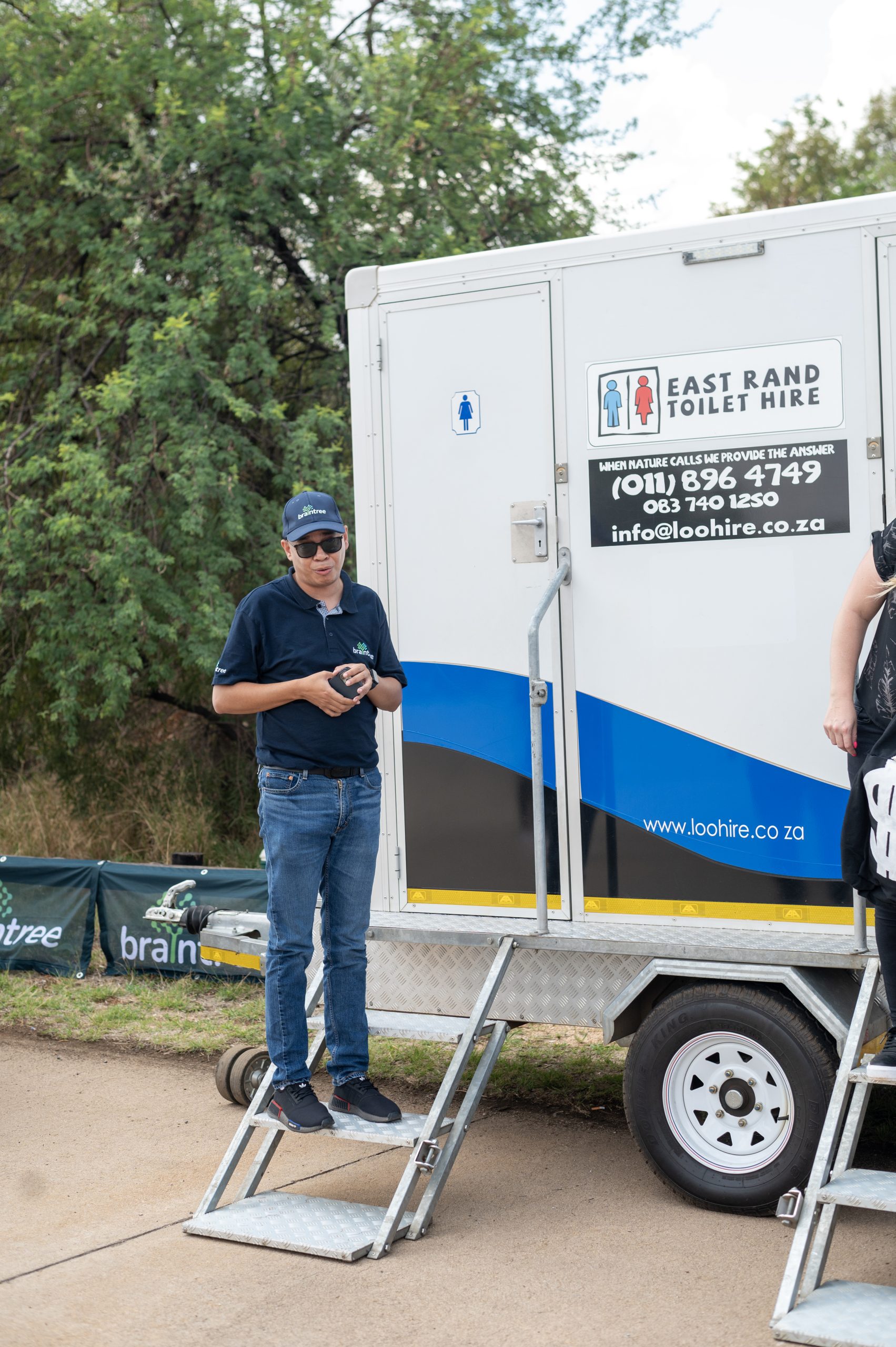 a Person standing on the stairs in front of a toilet hire trailer