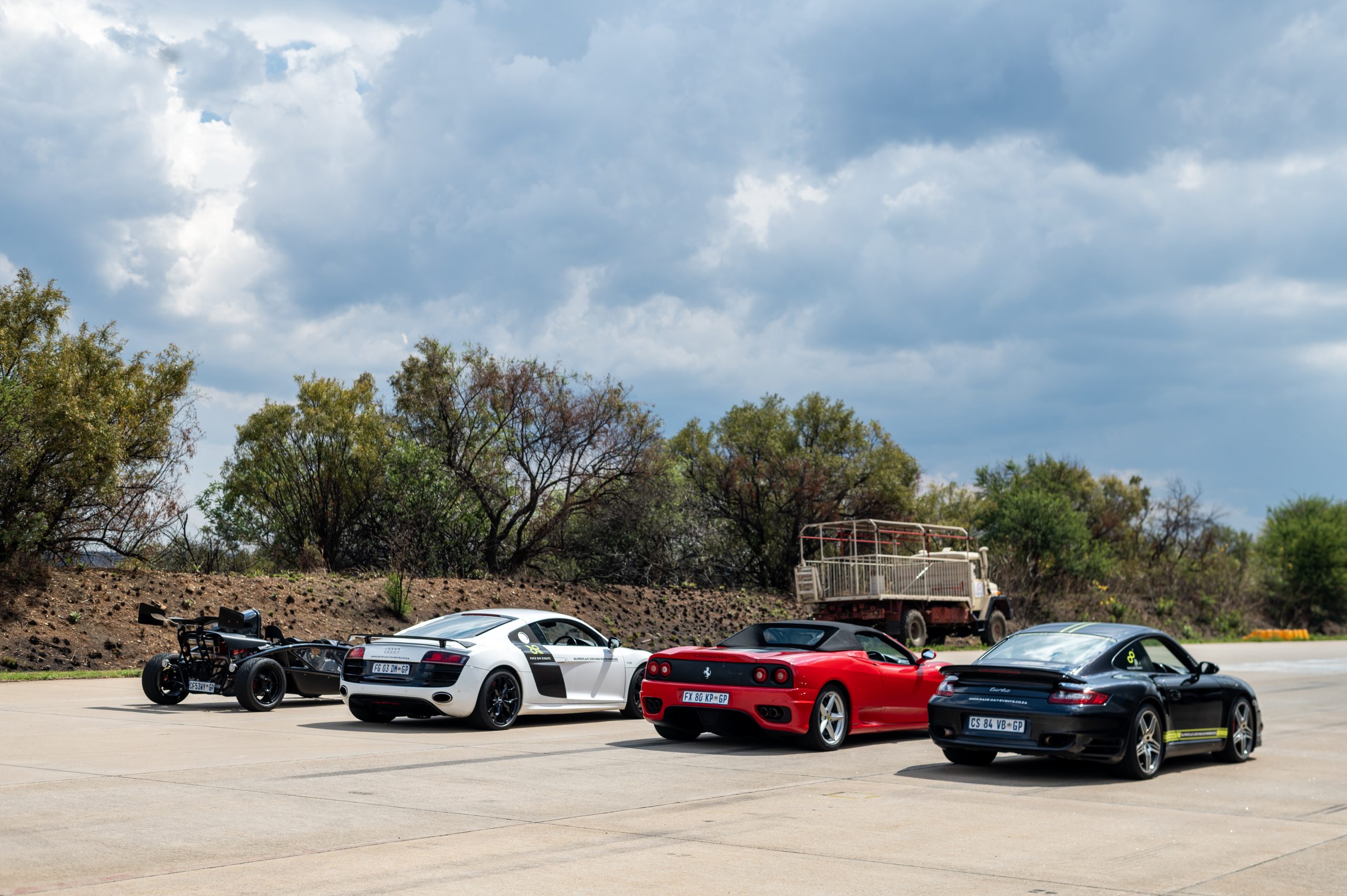 4 supercars standing next to one another in a row on a road.