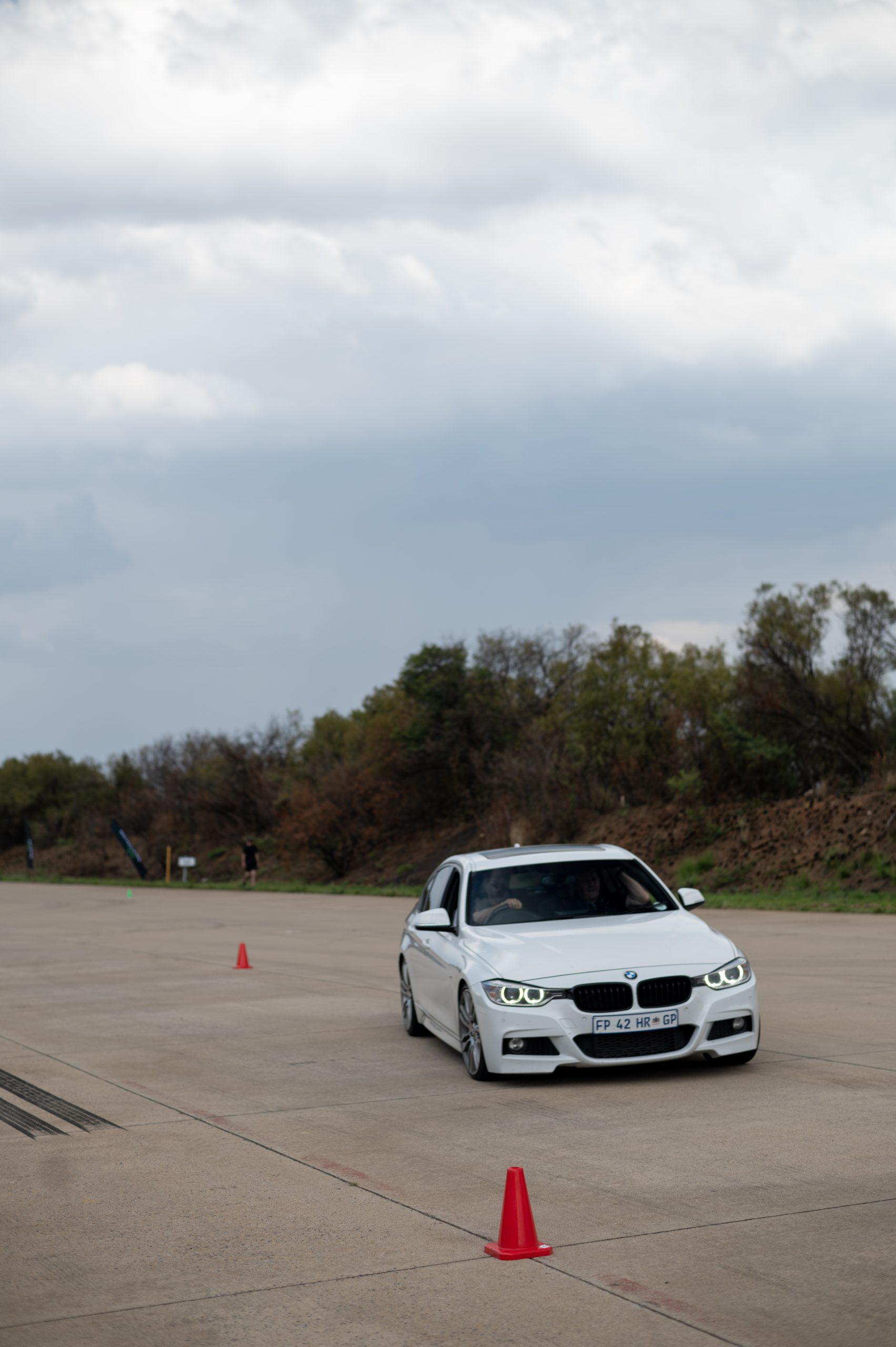 white BMW driving between 2 orange cones