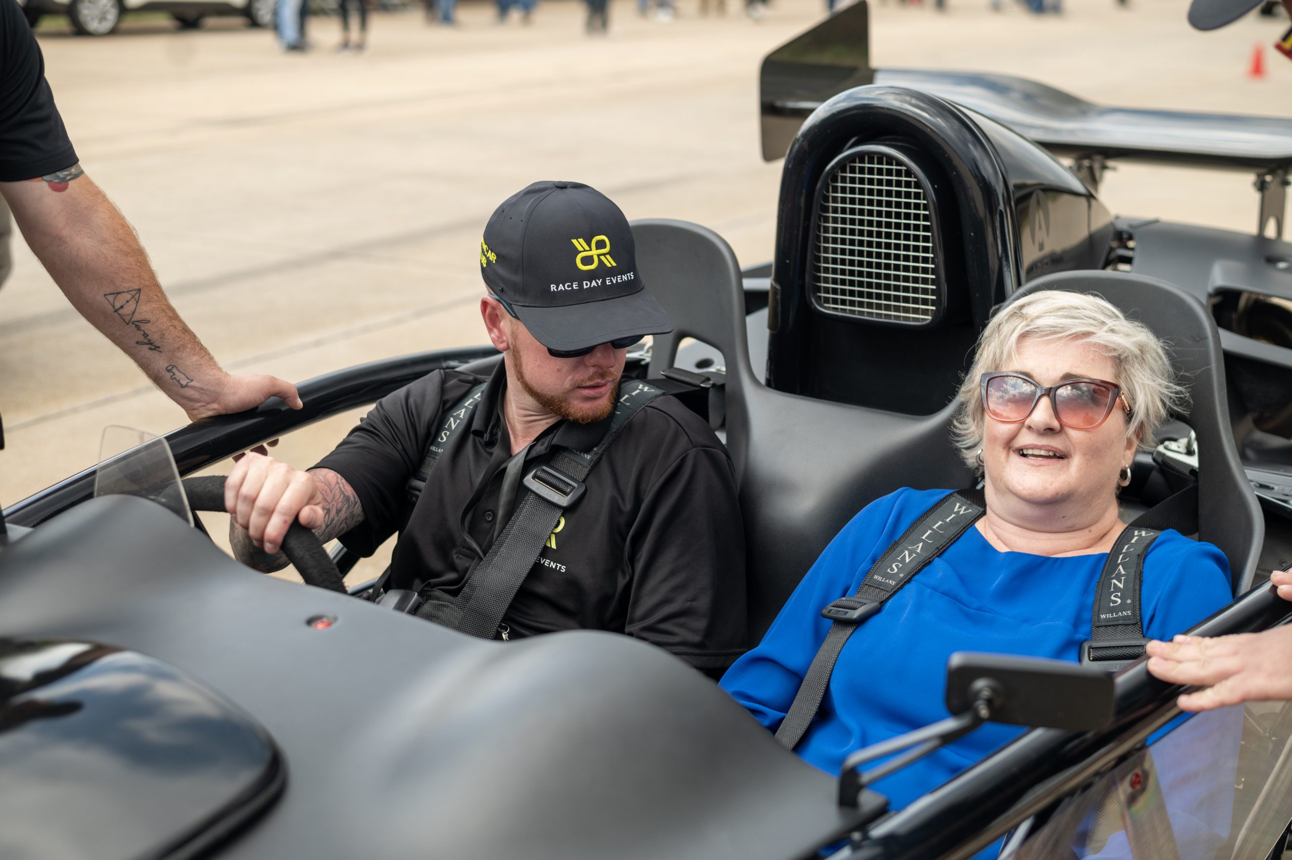 two people sitting in a small supercar without a roof - 2