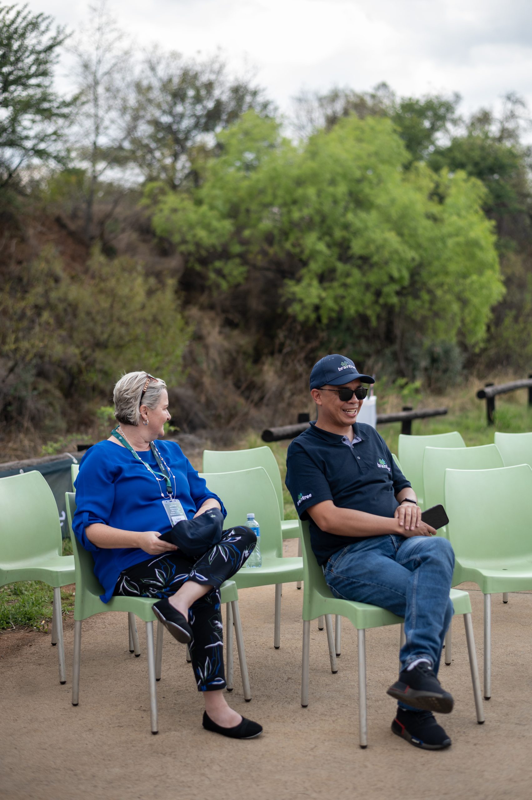 two Braintree employees sitting on plastic chairs next to a road